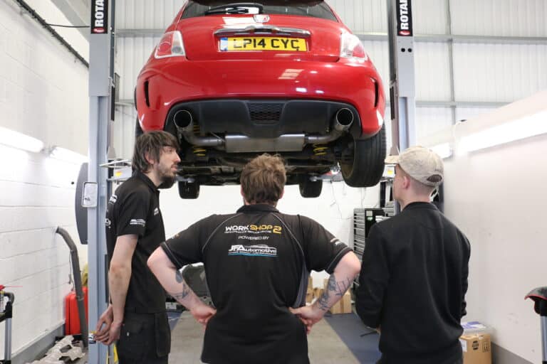 The JF Automotive team working under a car on the ramp